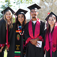 Four graduates pose for a picture at commencement