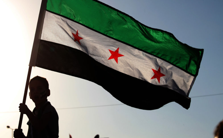 a boy waving the revolutionary Syrian flag with three stars.