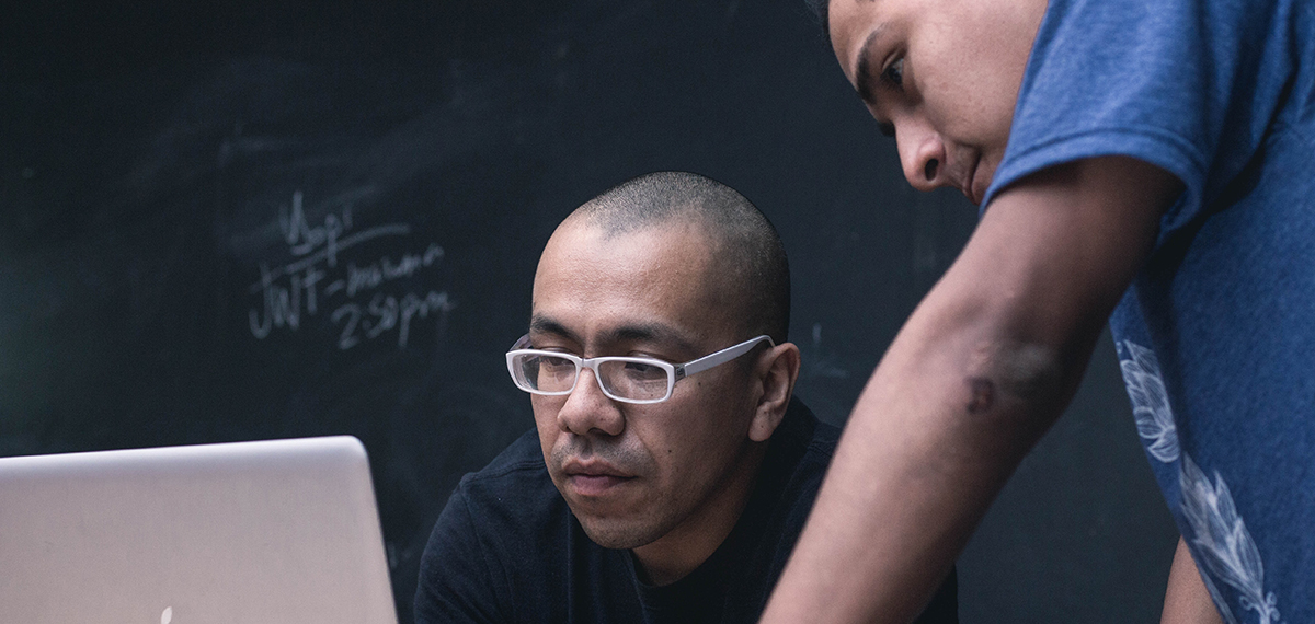A tutor looking over a student's shoulder at a laptop. Photo by Jose Aljovin on Unsplash.