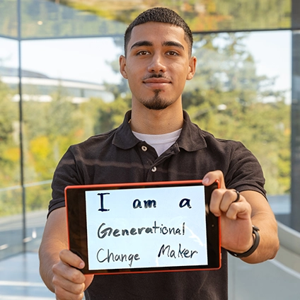 Alumnus Wolfgang Mundt holding a sign that says "I am a generational change-maker"