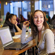 A young woman smiles while working on her computer