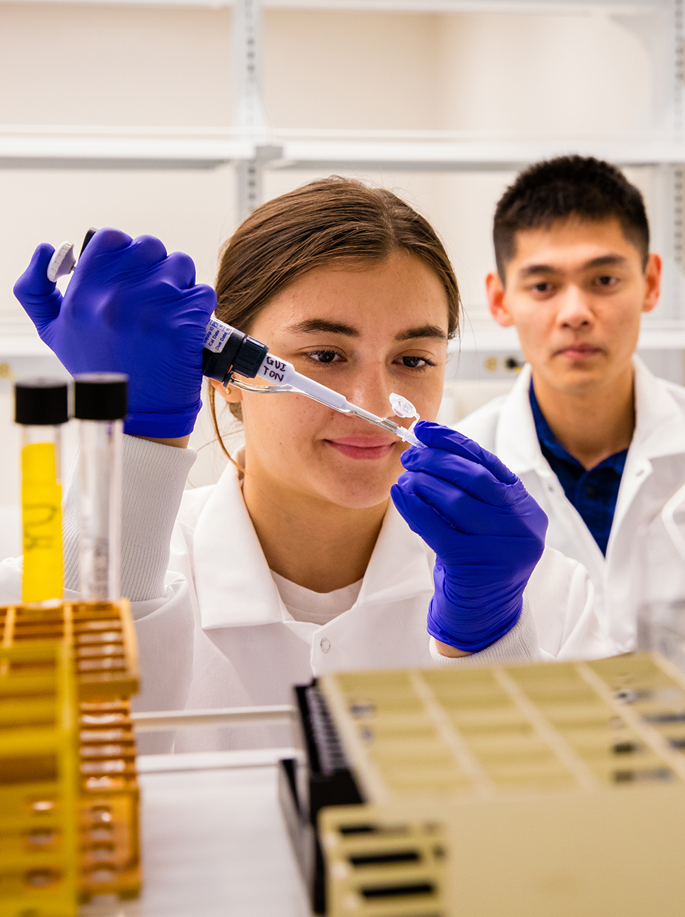 Two students in lab coats working in lab