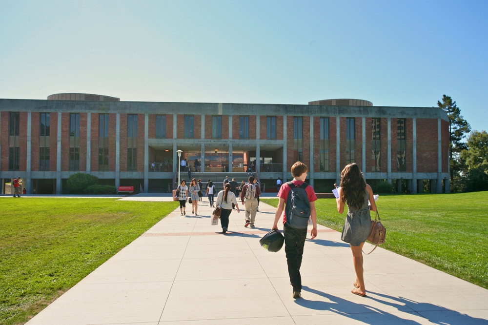 Students walking in front of big red building (Meiklejohn Hall)