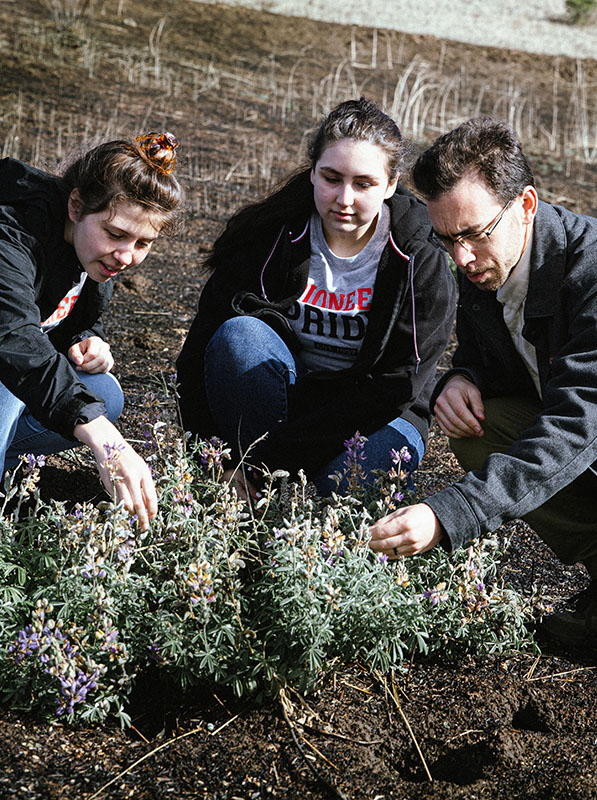 Professor and two students examine plants