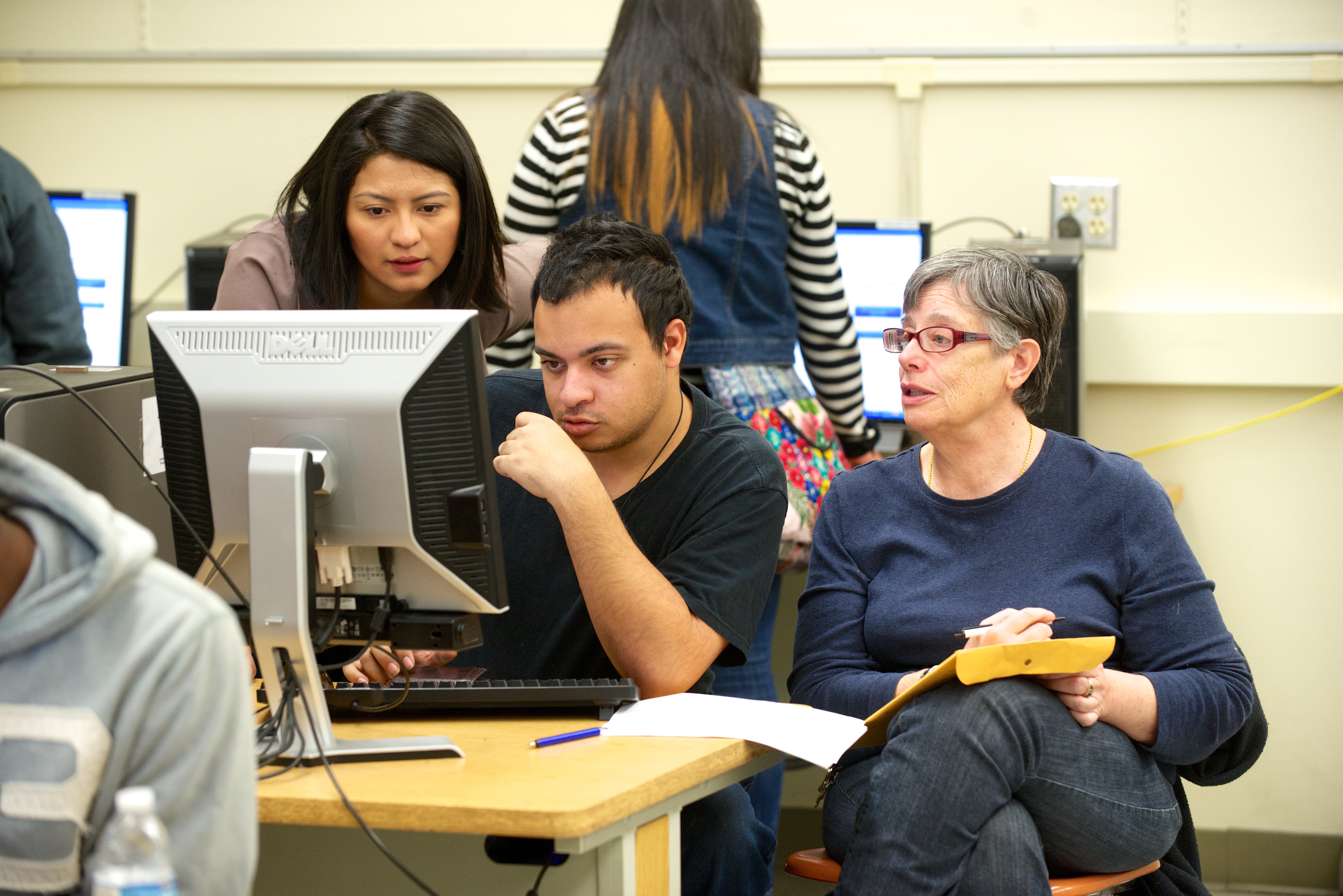 Student Working on Computer with Two Professors Helping