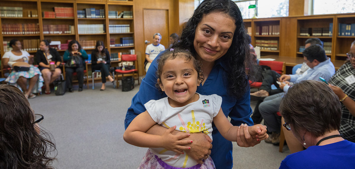 Woman holds up young daughter