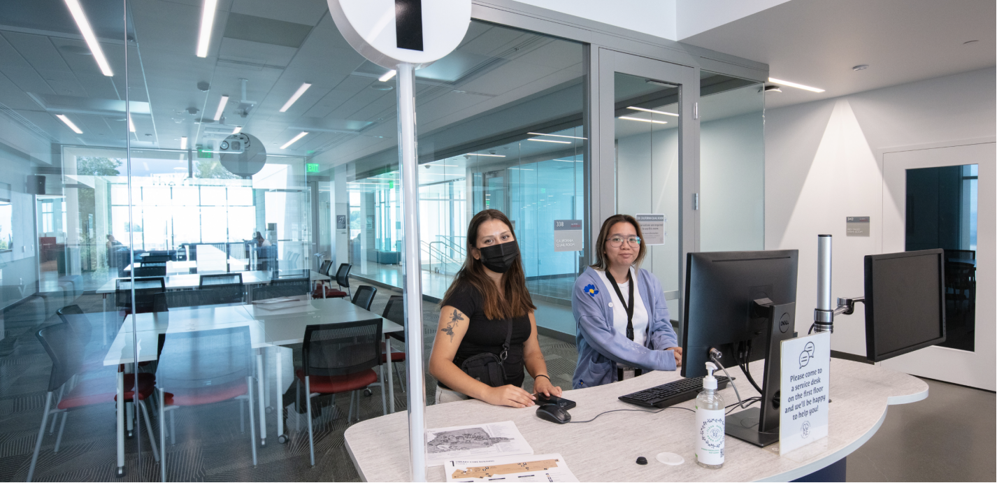 two people standing in front of a desk