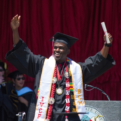  Student smiling and raising hand on stage