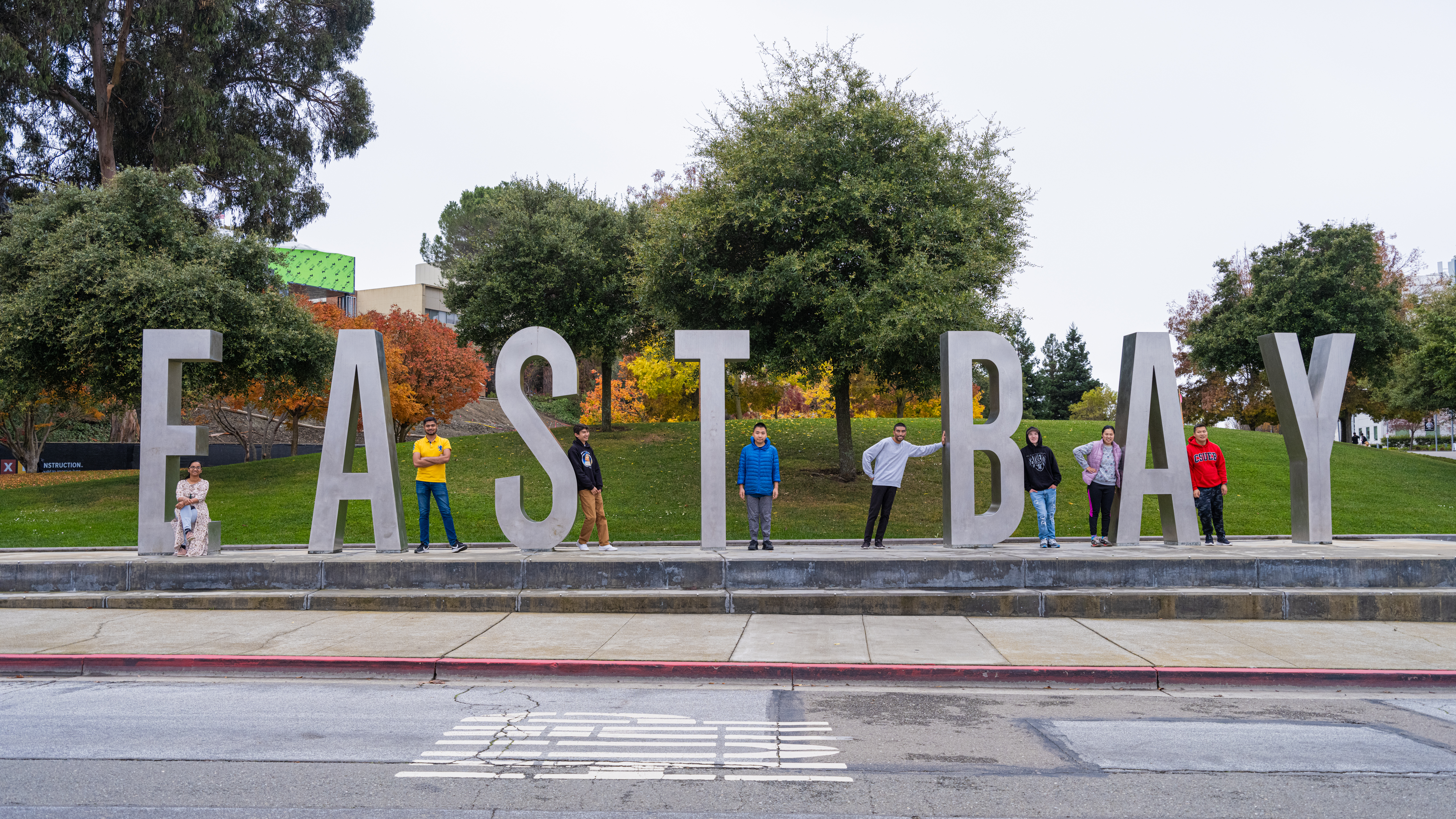 Think by the Bay students and peer mentors standing around the East Bay letters on campus