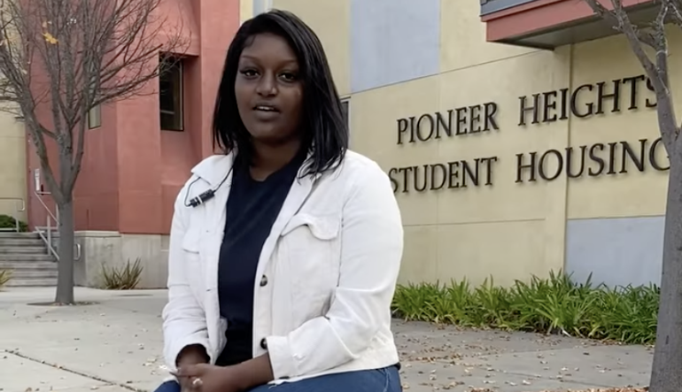 woman sitting in front of Pioneer Housing sign