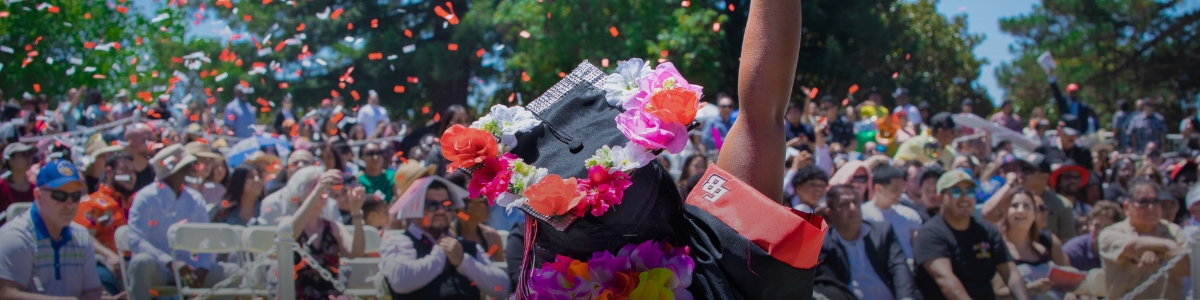 Graduate holding up her hand in celebration as confetti falls