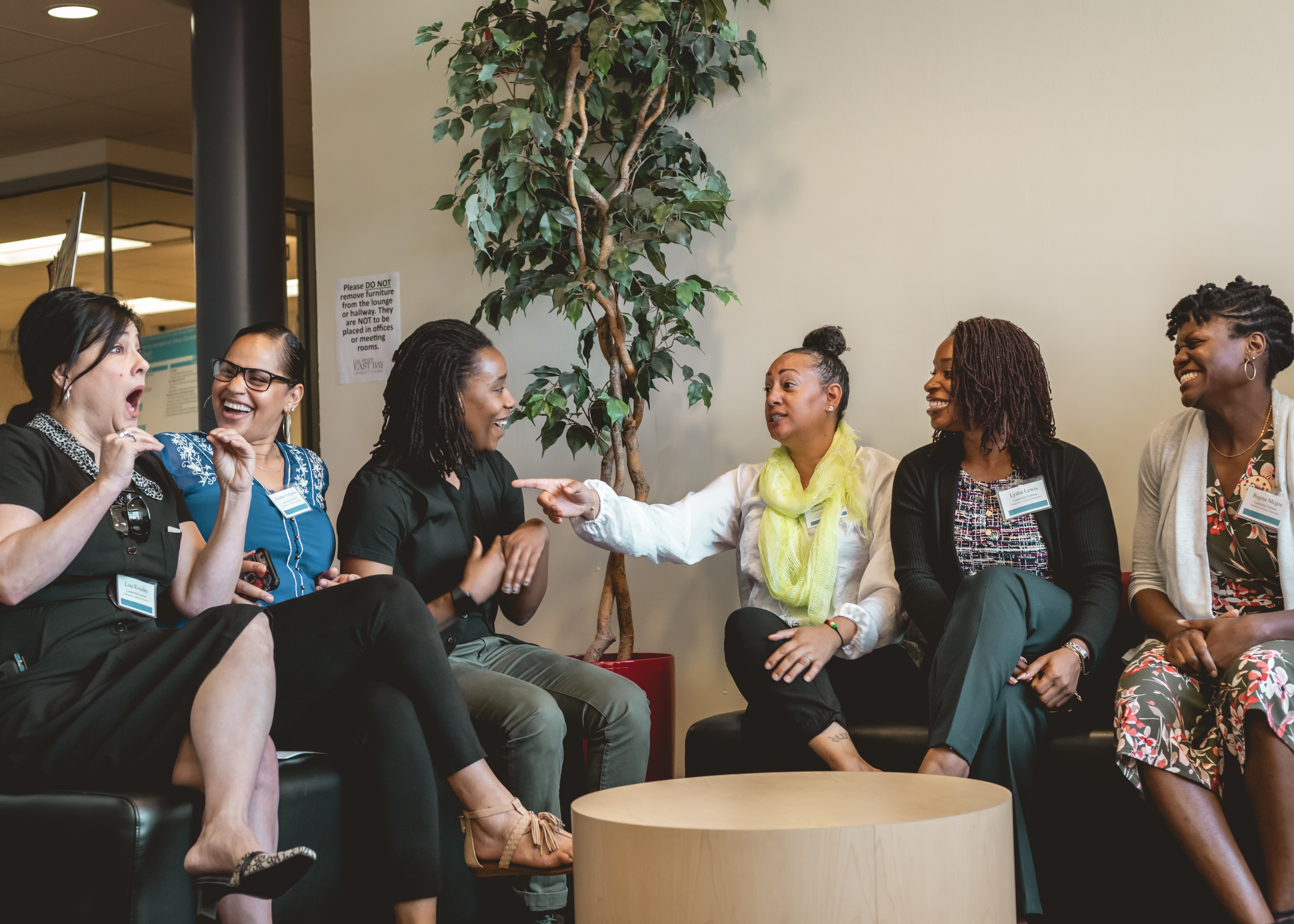 Photo shows students sitting next to each other in business attire, talking and laughing.