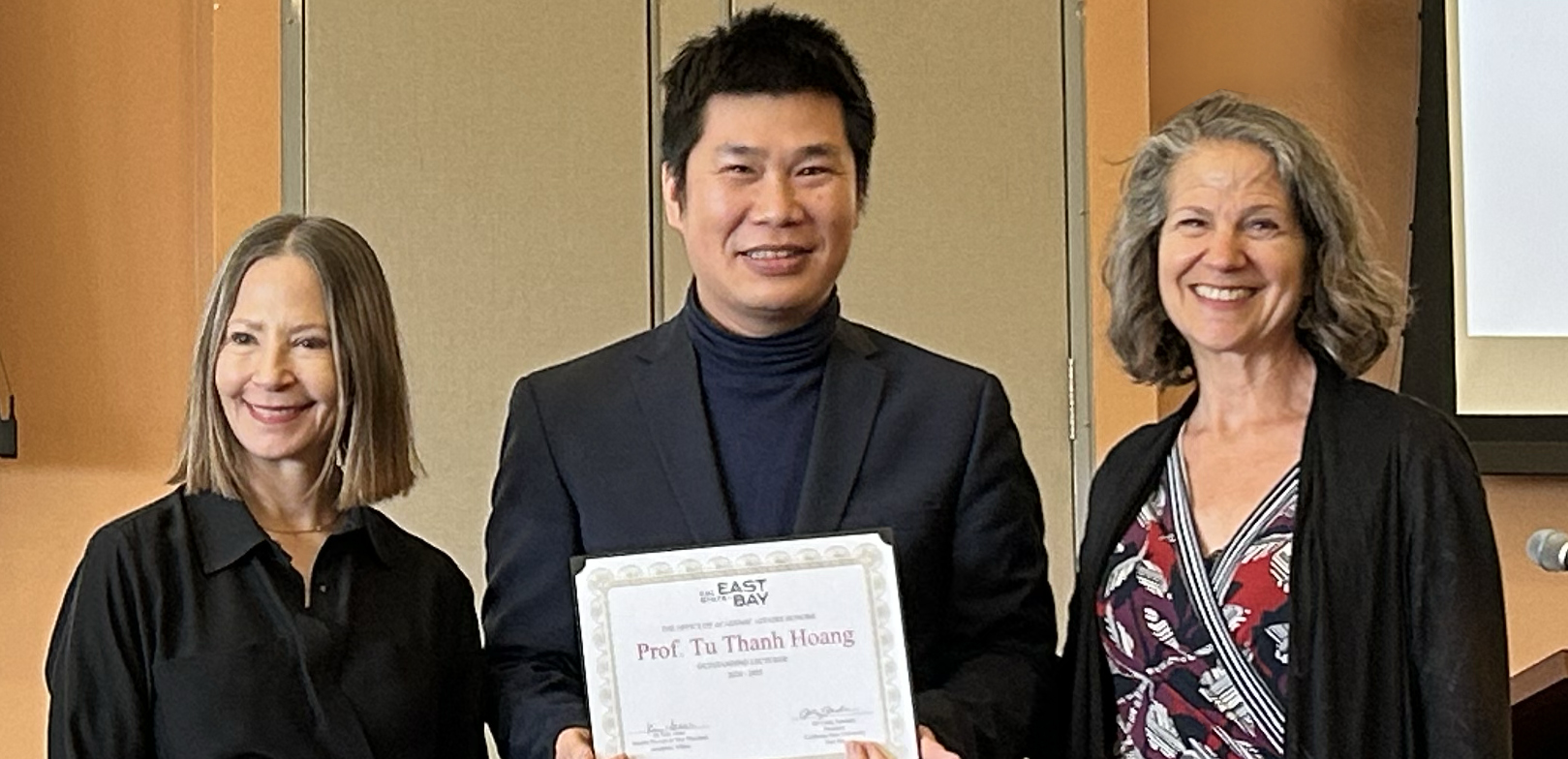 Photo of Tu Hoang at Faculty Awards with award certificate.