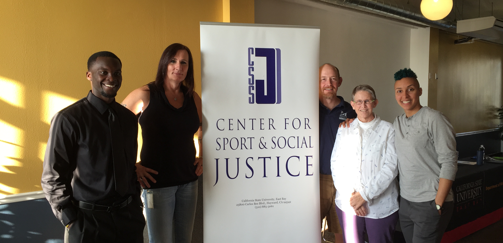 5 people standing next to logo