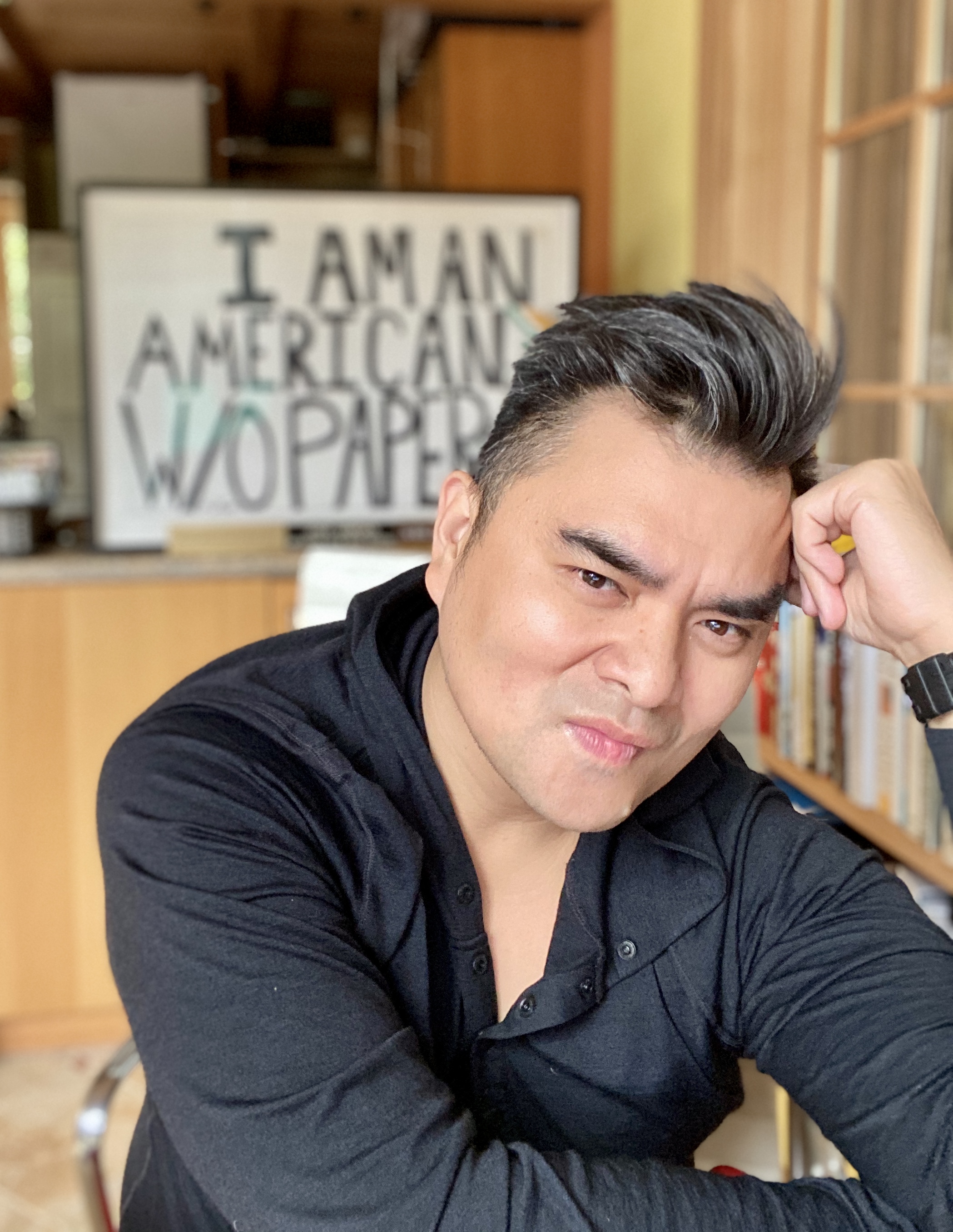 Jose Antonio Vargas wearing a black shirt, looking directly at the camera while propping his head on one hand.