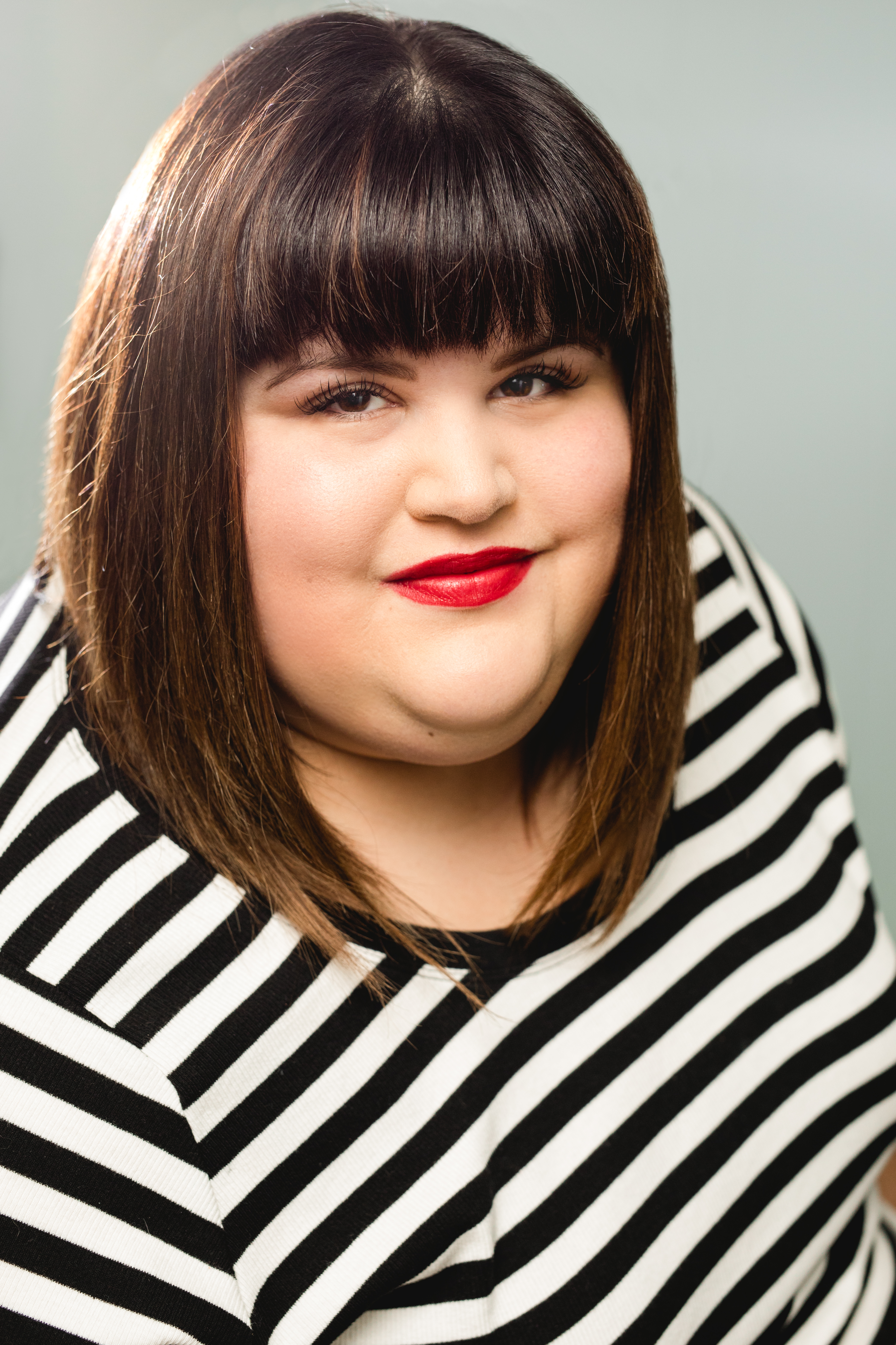 Julie Murphy smiling wearing red lipstick and a black and white striped shirt.