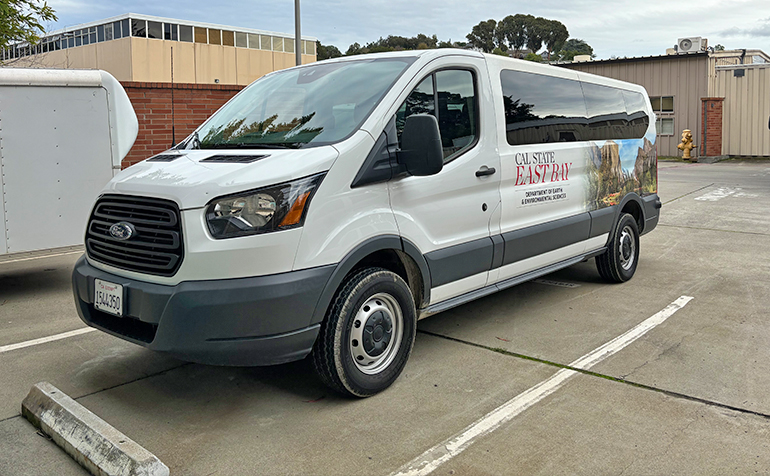 Image of Ford passenger van, with Cal State East Bay logo and scenery from Yosemite National Park on the side