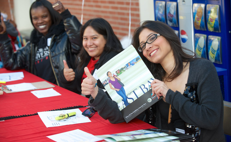 Student Staff Smiling While Holding CSUEB Folder