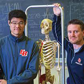 teacher with student standing in classroom 