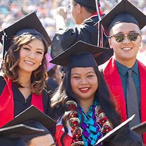three students standing graduating 