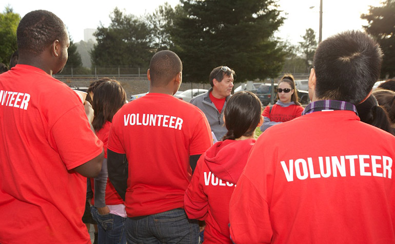 Volunteers in red shirts listen to directions