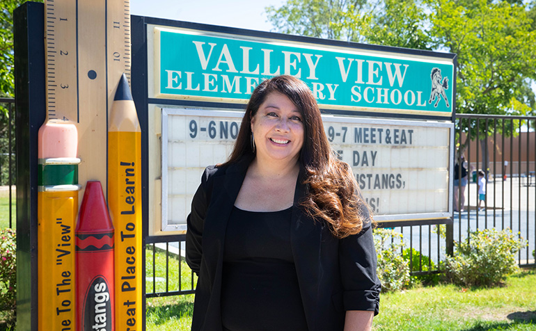 Teacher in front of elementary school sign