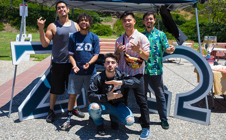 Students in a fraternity in front of sign