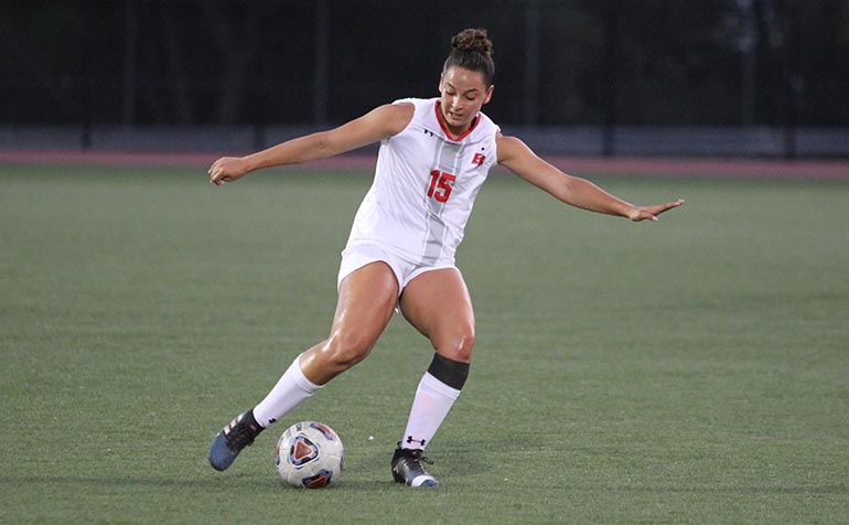 Female soccer player dribbles ball