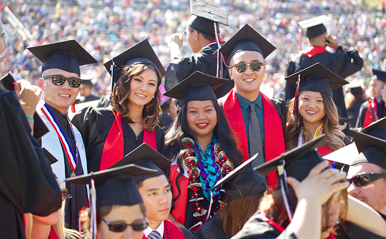 Students pose at graduation in cap and gown