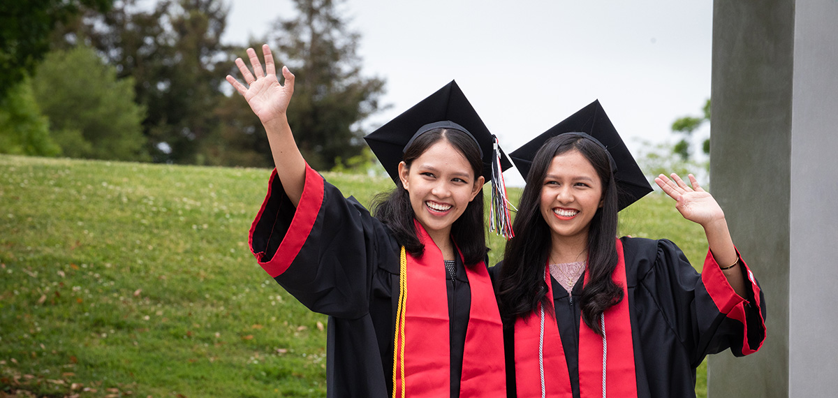 Twins wave at commencement.