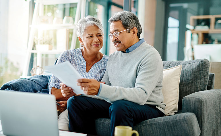 Man and woman look at paper on couch