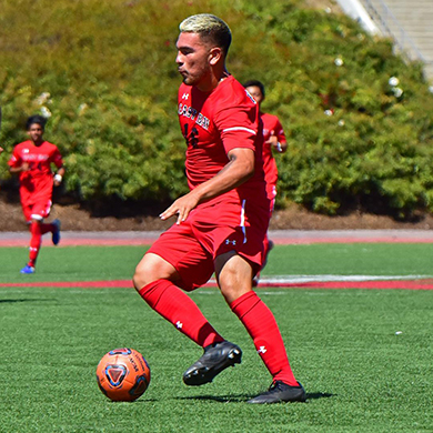  Male in red uniform dribbles a soccer ball