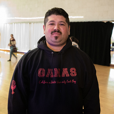  A male student wears a black sweatshirt with GANAS on it
