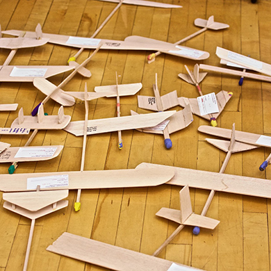  balsa wood airplanes lie together on a gym floor