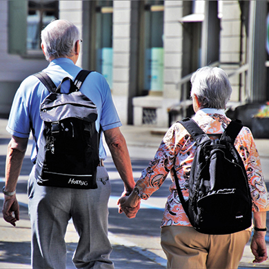  The backside of elderly man and woman who are holding hands while walking