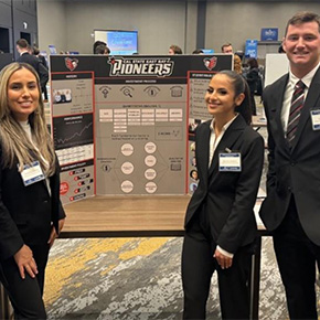 Three students standing with poster board 