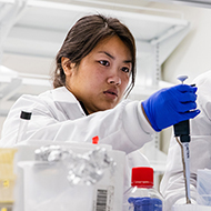 Student in lab coat conducts experiment