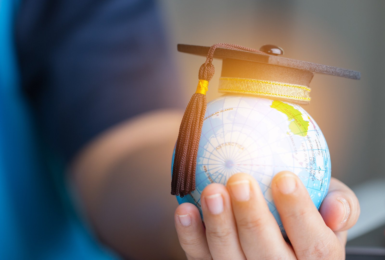 man holding globe with mortar board hat