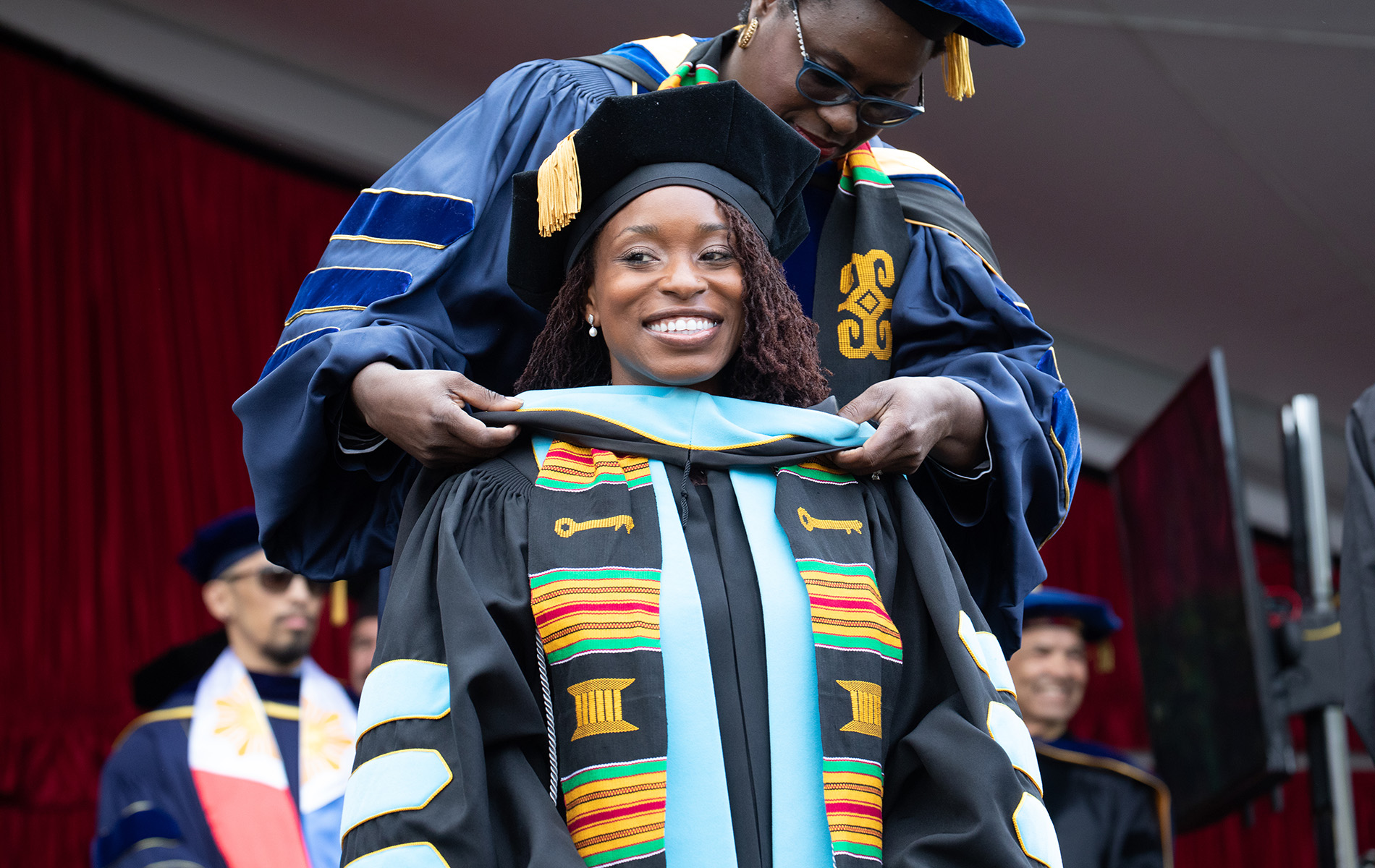 A student smiles in graduation cap and gown