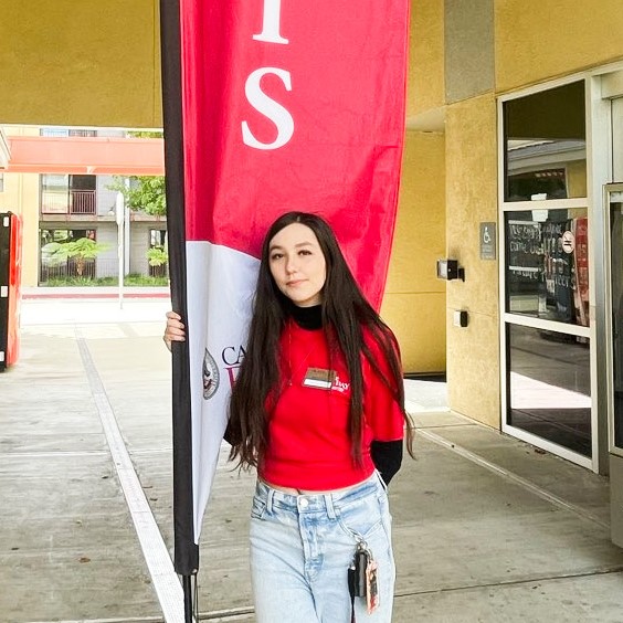 Front Desk Student Assistant holding a building flag