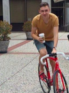 Young man on a bike holding a coffee