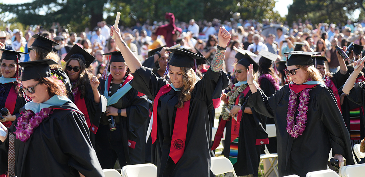 Students in their regalia celebrating as they walk to graduate