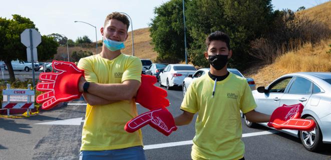 Two students in masks with big foam finger.