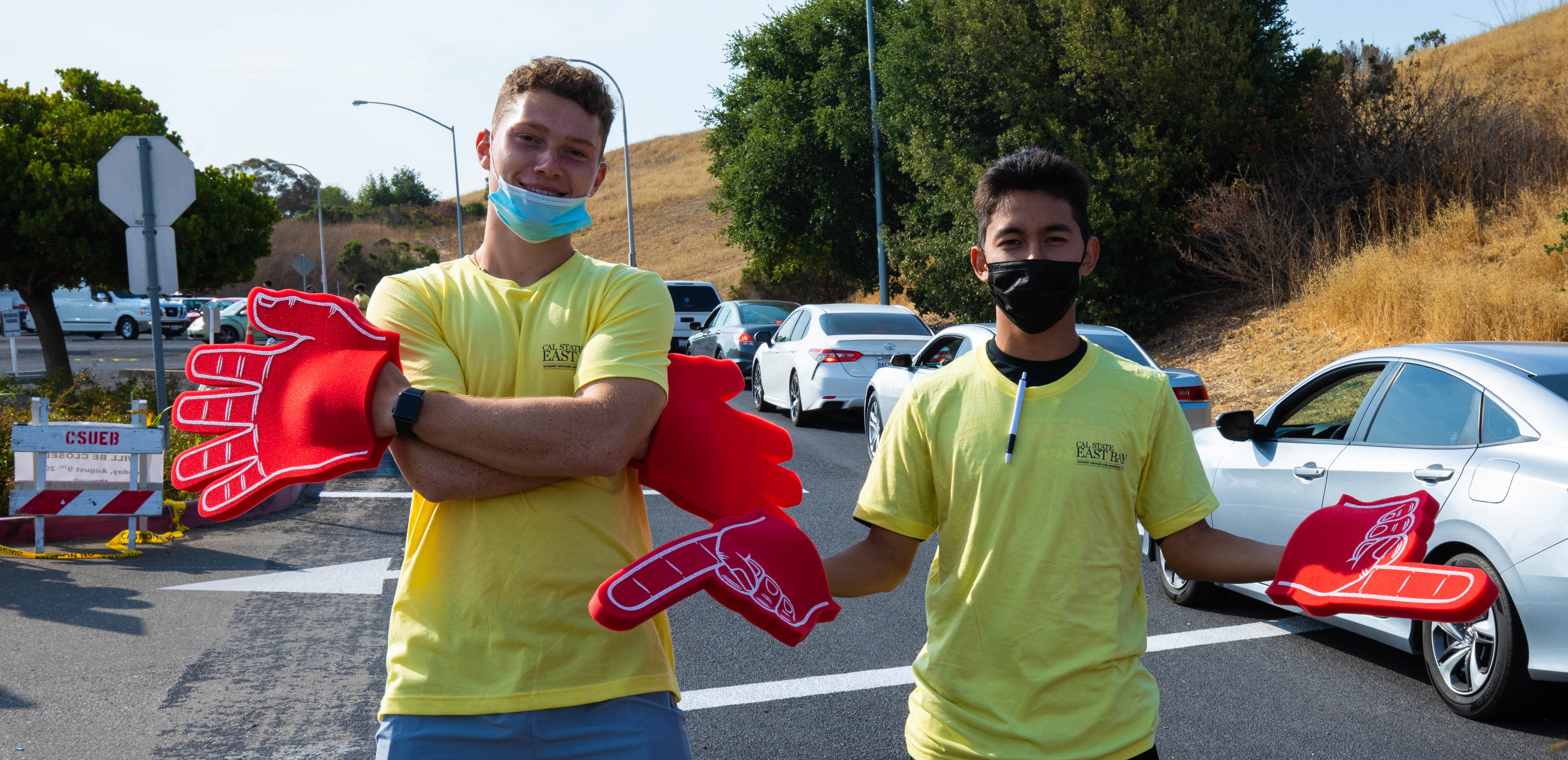 Two students in masks with big foam finger.