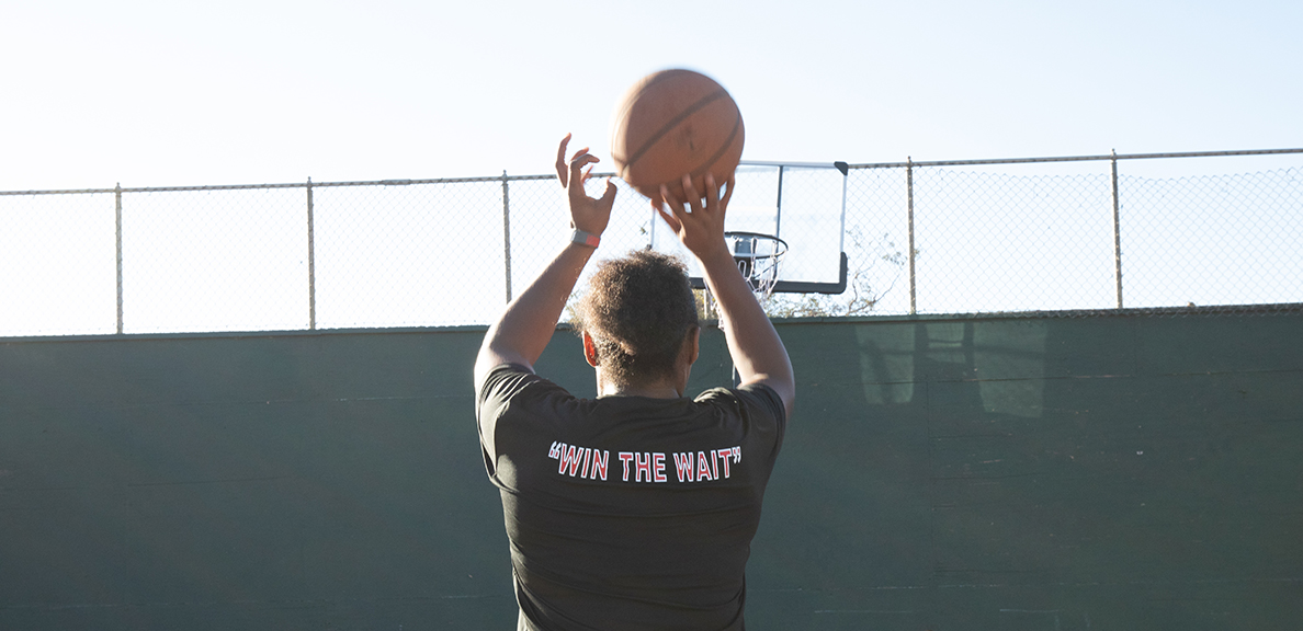 Female basketball player wearing Worth the Wait shirt shoots ball at hoop