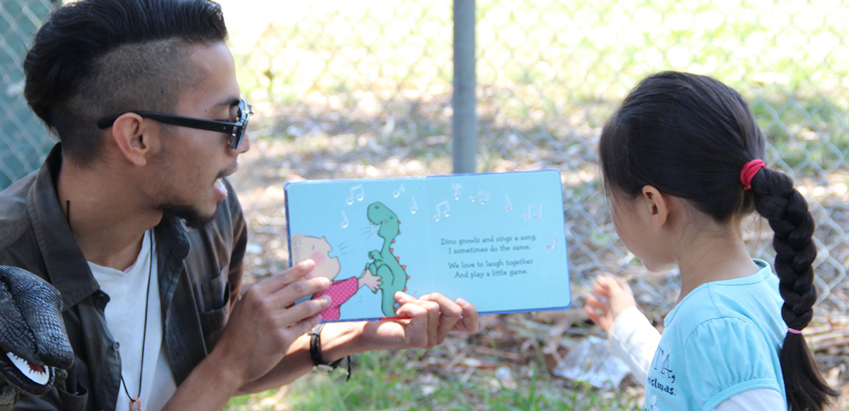 Male reads book to child outdoors