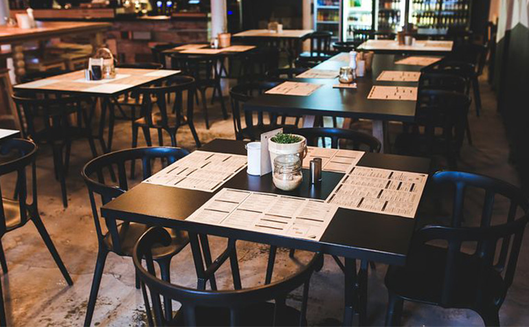Attend Alumni Event (image description: black tables at a restaurant)