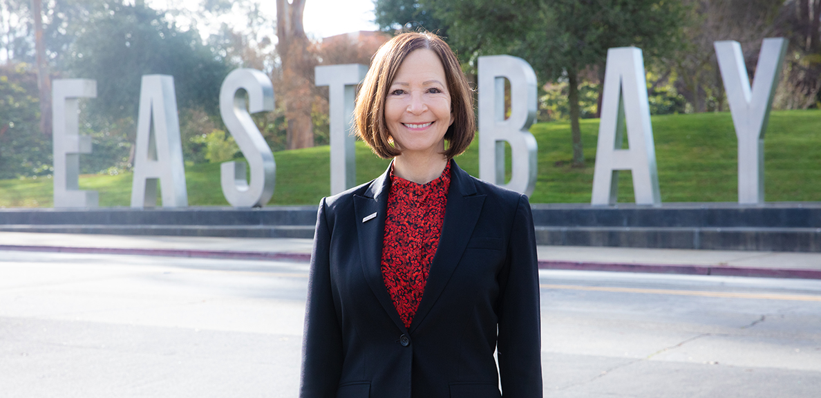 Cathy Sandeen stands in front of East Bay letters