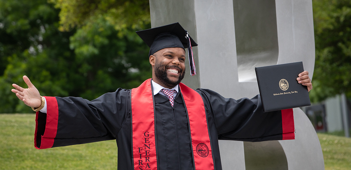 Graduate in cap and gown holds up diploma