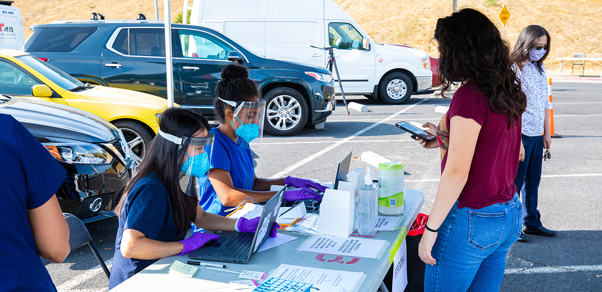 Nurses check in a student for COVID-19 testing in a parking lot